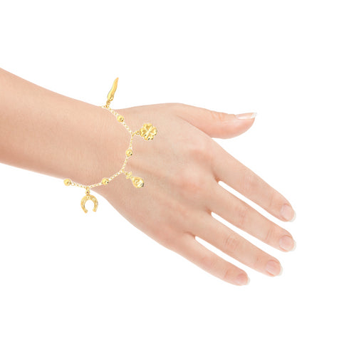 A hand adorned with the exquisite Mega Lucky Charm Anklet Bracelet glimmers gracefully. This chic accessory, crafted from 14k gold-filled material, boasts charms such as a figa hand, horseshoe, money bag, clover, and lucky chili—each representing spiritual protection. Set against a plain white background, it captures both style and significance.